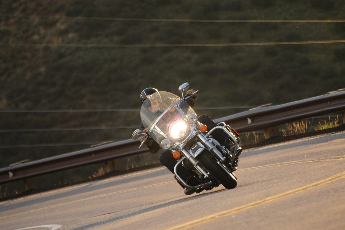 Rider leaning motorcycle with engine guards around curve