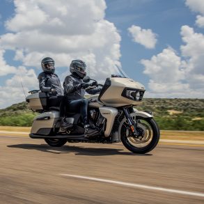An image of a rider and passenger cruising down a road on the Indian Pursuit Dark Horse.